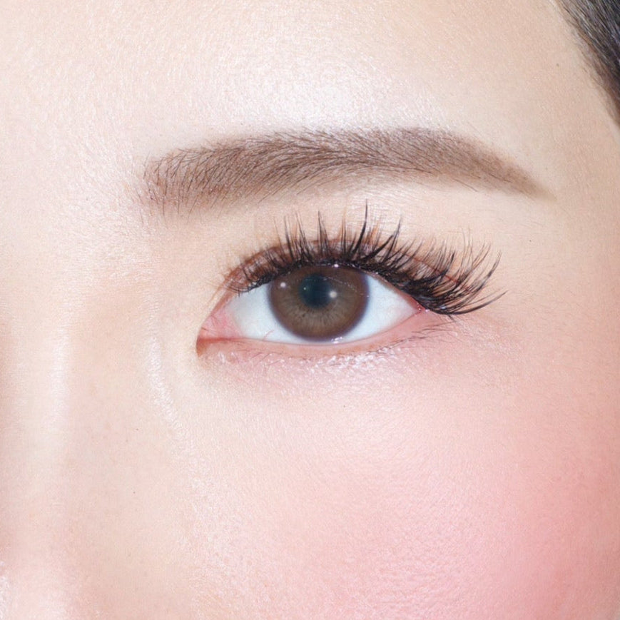 A close-up of an eye with Lashy Lab’s CHIC GIRL Wispy, Trendy, Cat Eye cluster lashes and defined brows. Smooth skin and subtle blush highlight easy application for fake eyelashes that stay put for weeks.