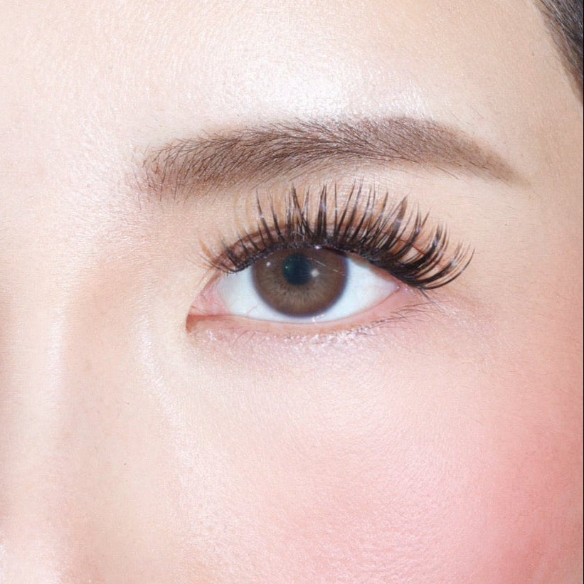 Close-up of a brown eye adorned with Lashy Labs NIGHT OUT cluster lashes for a full, voluminous, sassy look and a well-groomed brow. The skin is smooth with a soft natural blush on the cheek.