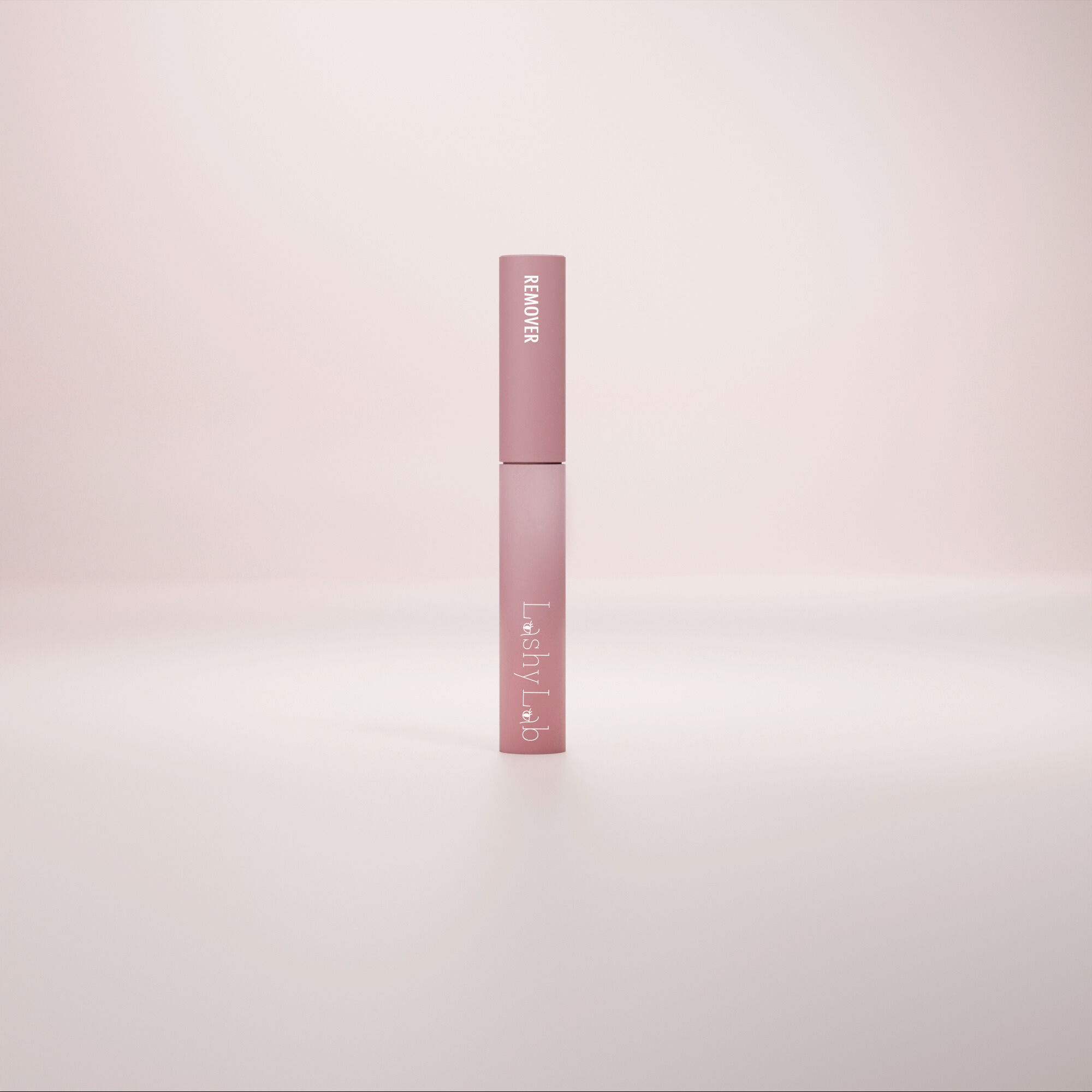 A pink tube labeled Lashy Lab LASH OFF REMOVER stands upright on a softly lit background, its minimalist design highlighting its use for cluster lashes against a gentle gradient backdrop.