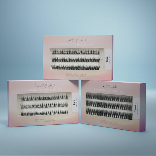 Three pink boxes of Lashy Lab’s PRE-GLUED LASHES MIX-MATCH BUNDLE in Wispy, Flare, and Flutter styles are shown against a blue background—ideal for easy DIY lash extensions that last for weeks.
