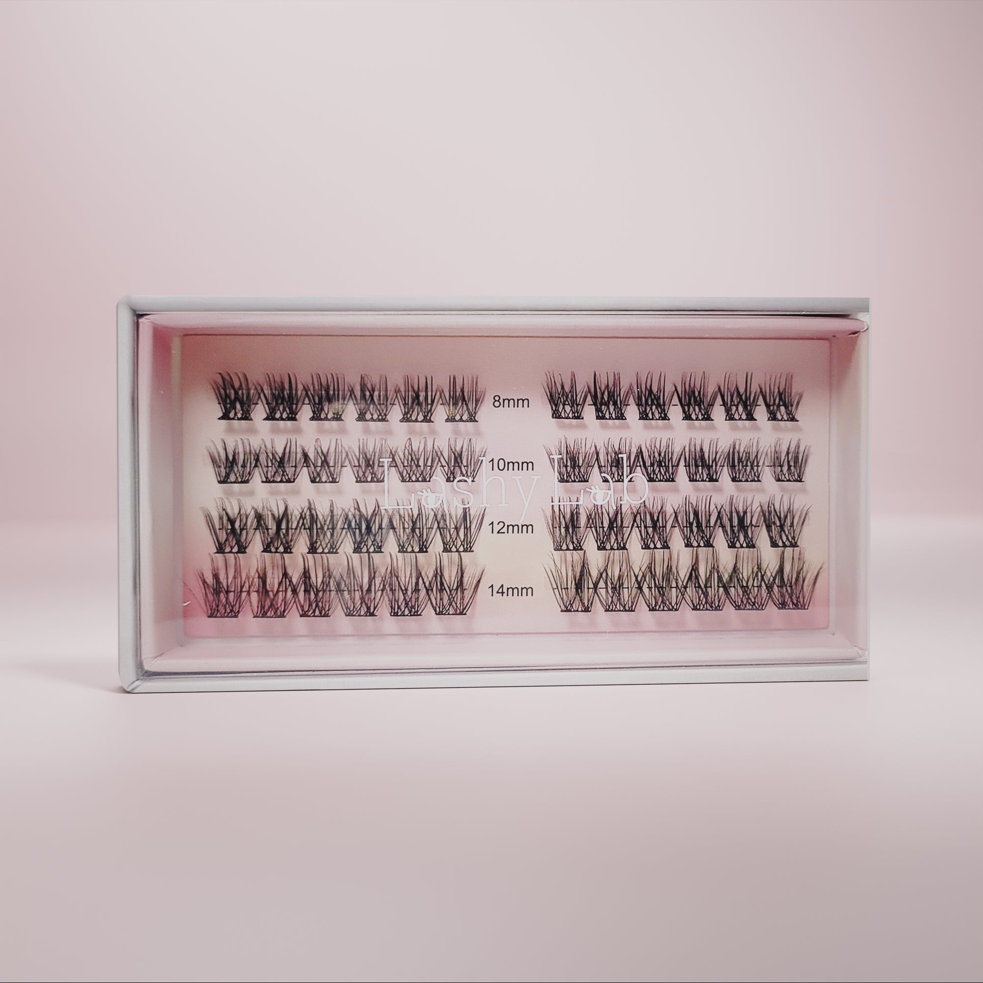 A box of CHIC GIRL Wispy, Trendy, Cat Eye pre-glued lashes by Lashy Lab, arranged in rows by length (8mm–14mm) on a pink background—ideal for those wanting long-lasting fake eyelashes.