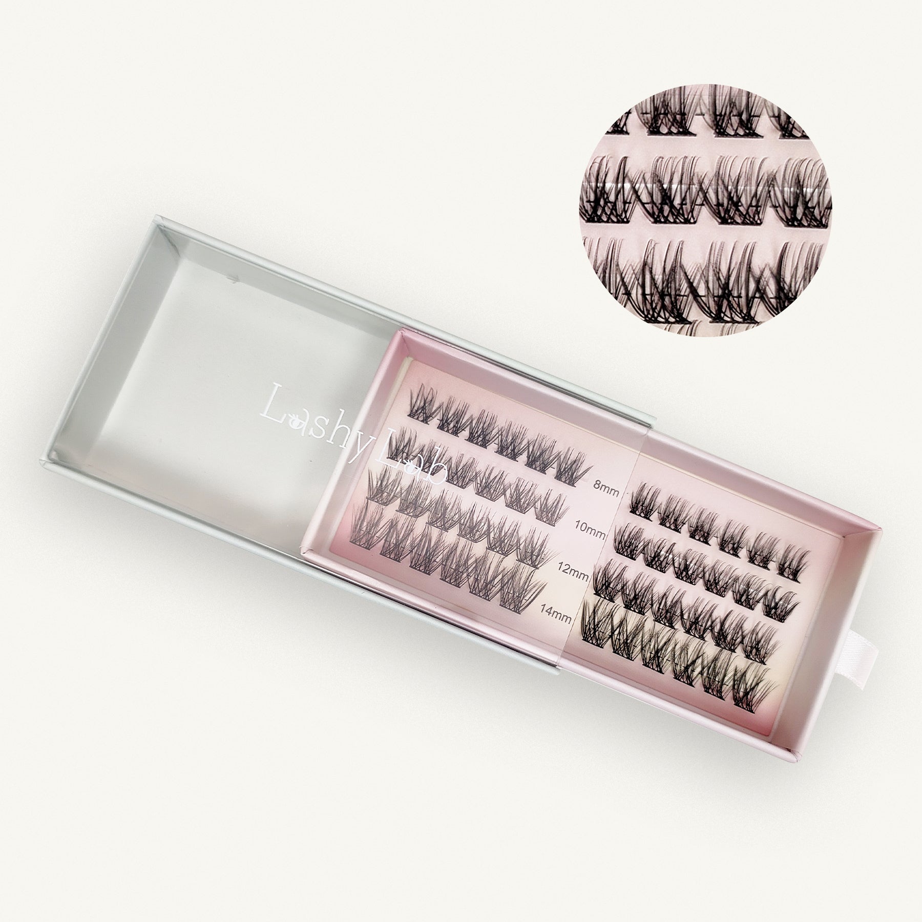The Lashy Lab CHIC GIRL Wispy, Trendy, Cat Eye cluster lashes come in an open pink and clear case with four rows labeled 8mm, 10mm, 12mm, and 14mm. An inset highlights the individual clusters for easy application.
