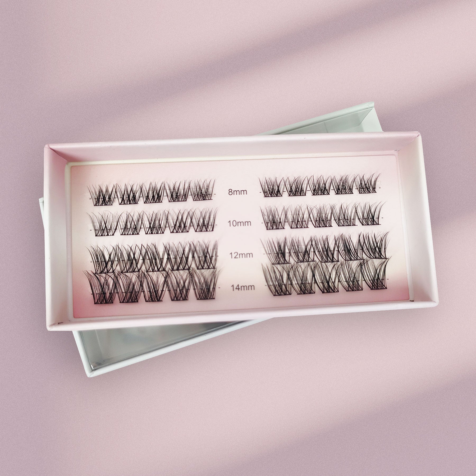 The Lashy Lab MOONLIGHT - Subtle, Light, Flare underlash extensions come in a pink box with four rows of cluster lashes—8mm, 10mm, 12mm, and 14mm—neatly displayed on a soft pink surface for easy application.