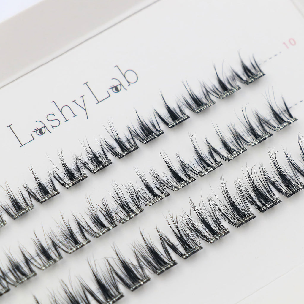 Close-up of Lashy Lab BARE PRE-GLUED LASHES SET, featuring a white tray with multiple rows of neatly arranged black cluster lashes for DIY eyelash extensions.